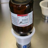 Solvent bottle cleaning and drying equipment. Detailed view on bottle during cleaning.
